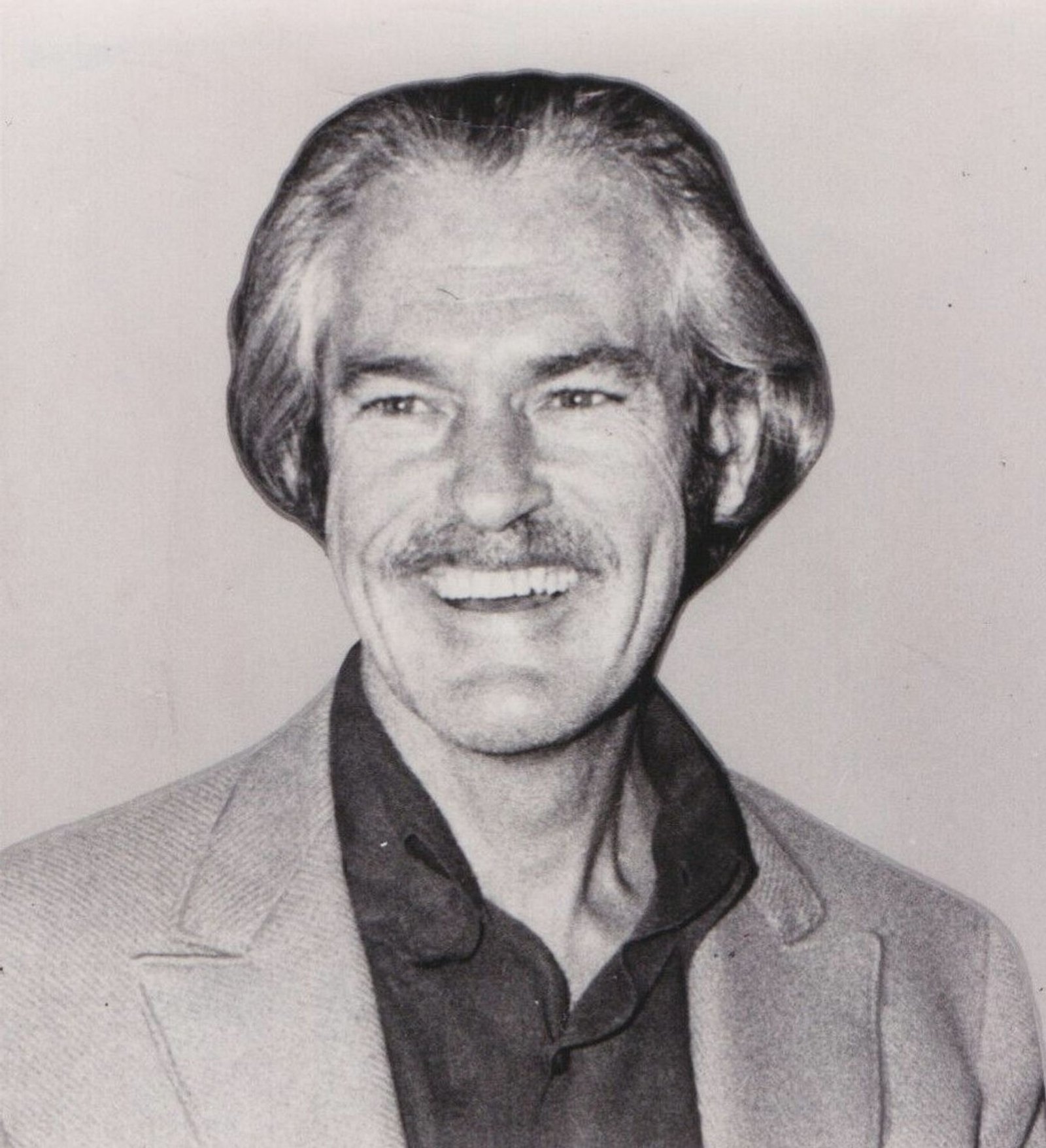 Black-and-white 1970 portrait of Timothy Leary, smiling and wearing a jacket over a dark shirt.