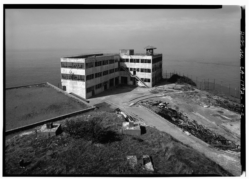 Black-and-white view of the Alcatraz Industries Building beside San Francisco Bay.